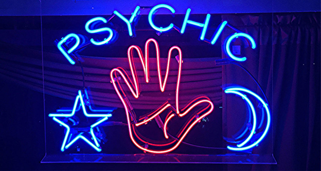 Blue Psychic neon sign, with star and moon sliver, and red open hand in the middle.