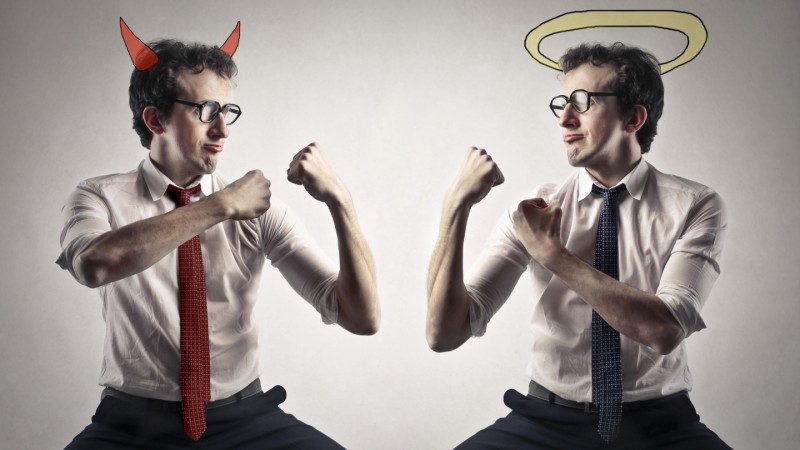 Two guys in ties, one with a halo one with devil horns, fists up, ready to fight.