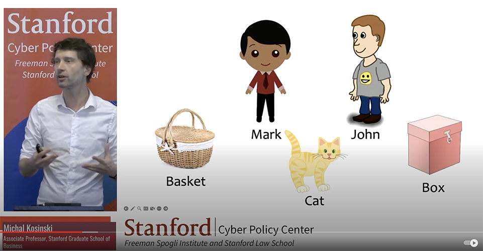 A presentation slide showing a split-screen design. On the left, a man wearing a white shirt is speaking in front of a red backdrop that reads "Stanford Cyber Policy Center." His name, "Michal Kosinski," and title, "Associate Professor, Stanford Graduate School of Business," are displayed in a red banner at the bottom.

On the right, the slide contains cartoon-style illustrations of a boy labeled "Mark," a boy labeled "John," a wicker "Basket," a yellow-striped "Cat," and a pink "Box." The objects and characters are arranged on a plain white background. The bottom banner reiterates the Stanford Cyber Policy Center branding.